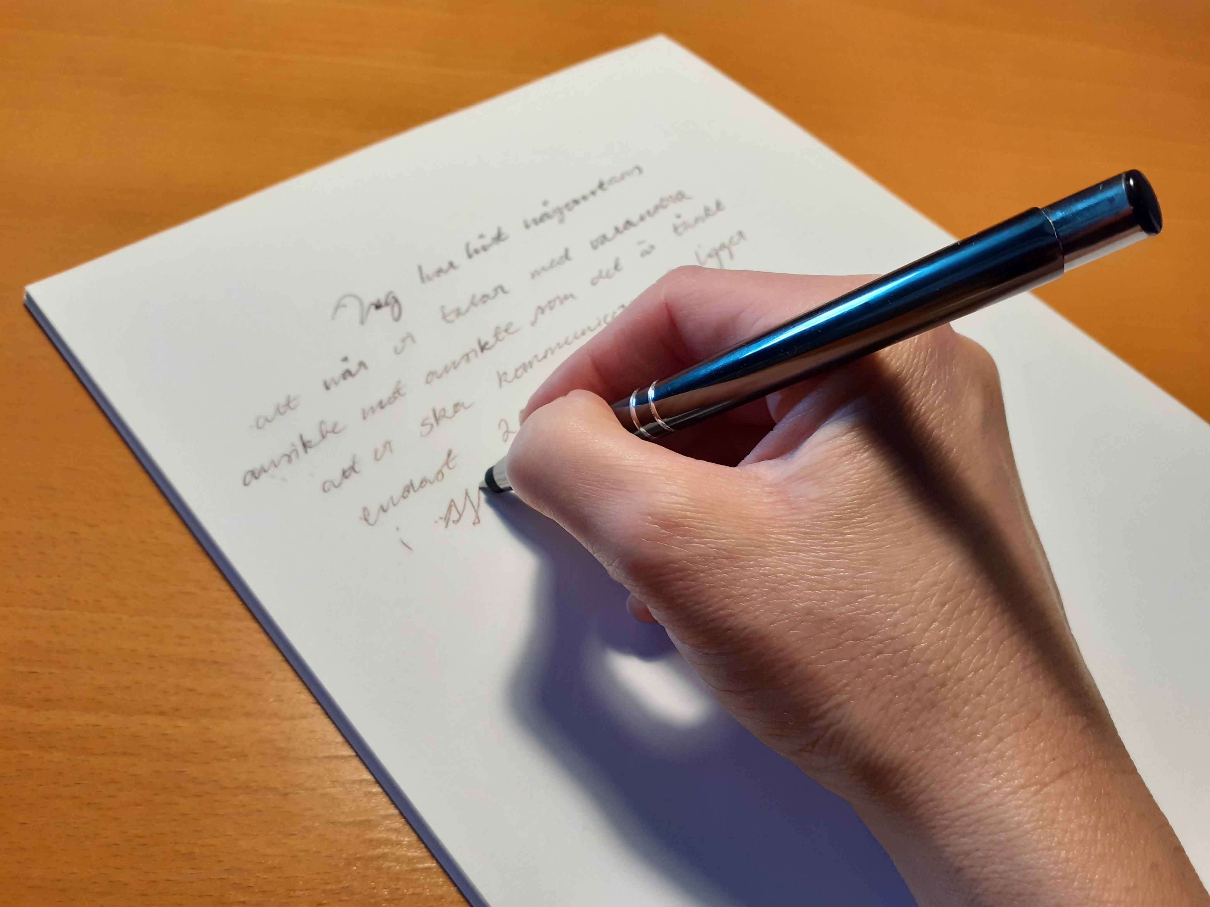 En hand med en penna som skriver på ett papper